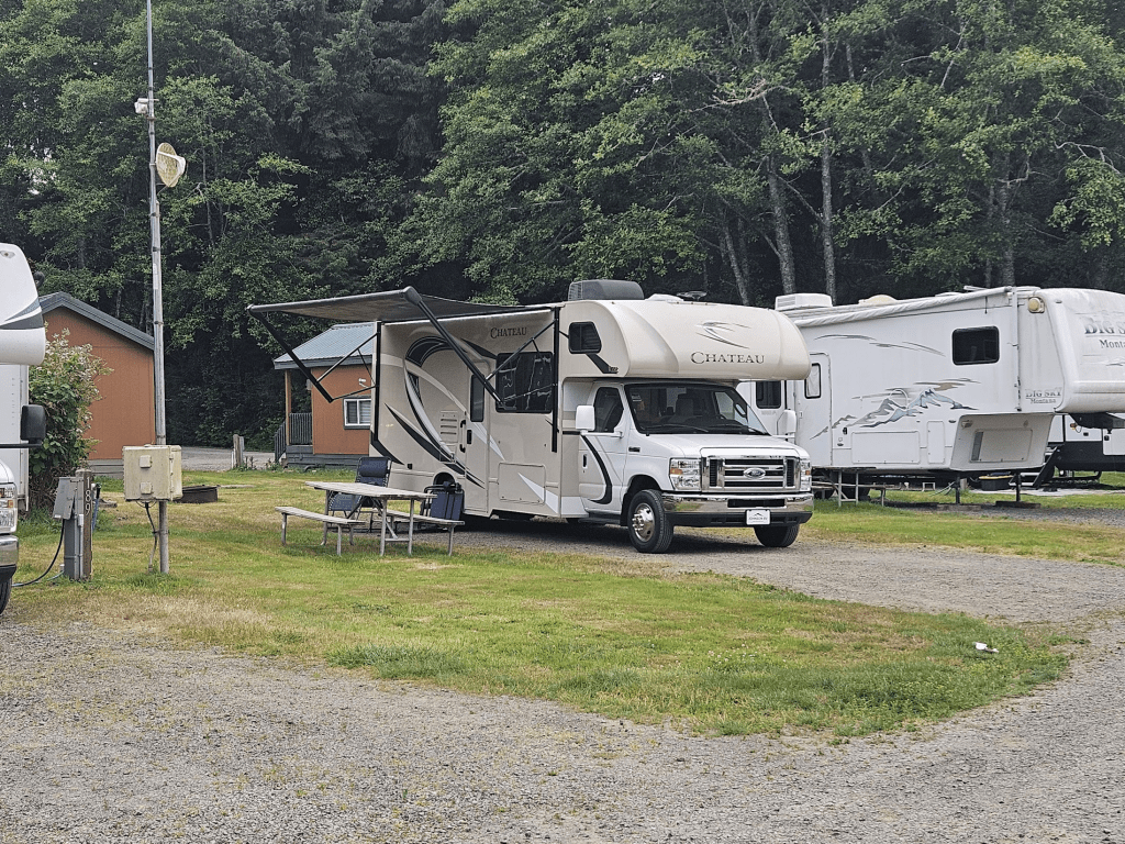 Annie the RV is parked in a campground with the awning extended and a picnic table nearby.